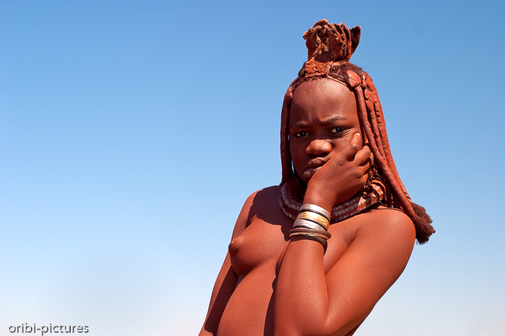 *Skeptisch ...*<br><br>... schaut diese junge Himba-Lady auf den Mann mit der Kamera.
Zwar verirren sich mittlerweile immer mehr Touristen in das schwer zugängliche Kaokoveld, aber all zu häufig bekommen die nomadischen Hirten Weiße nicht zu Gesicht - schließlich wurde dieser Volksstamm erst vor ca. 30 Jahren entdeckt.<br><br>